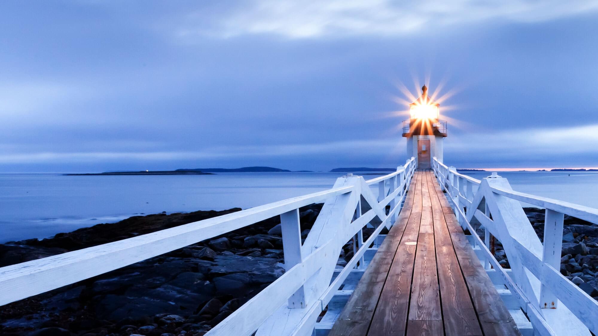 A lighthouse at the end of a wooden jetty.